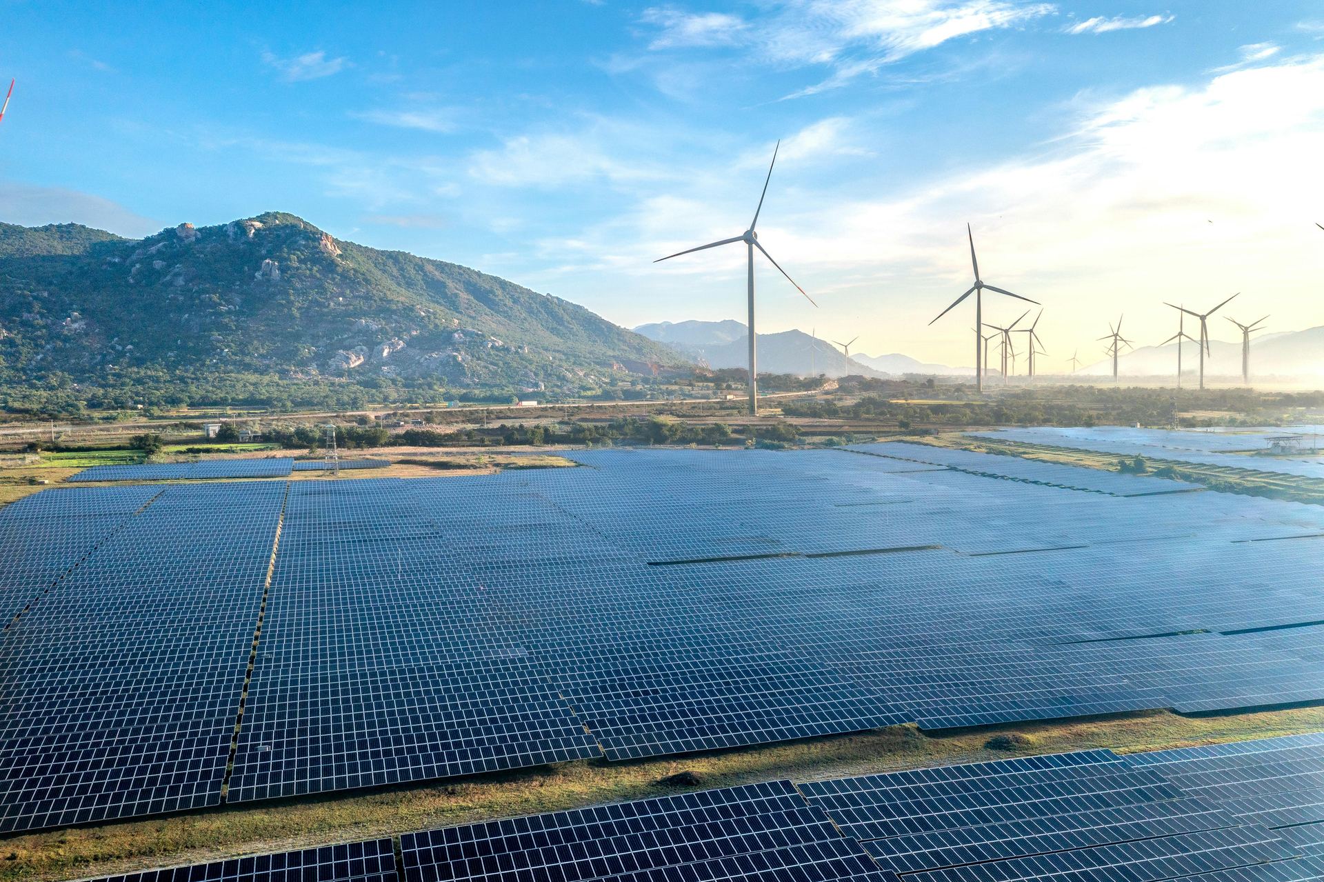Centrale solaire et éoliennes dans un paysage de montagne au lever du soleil